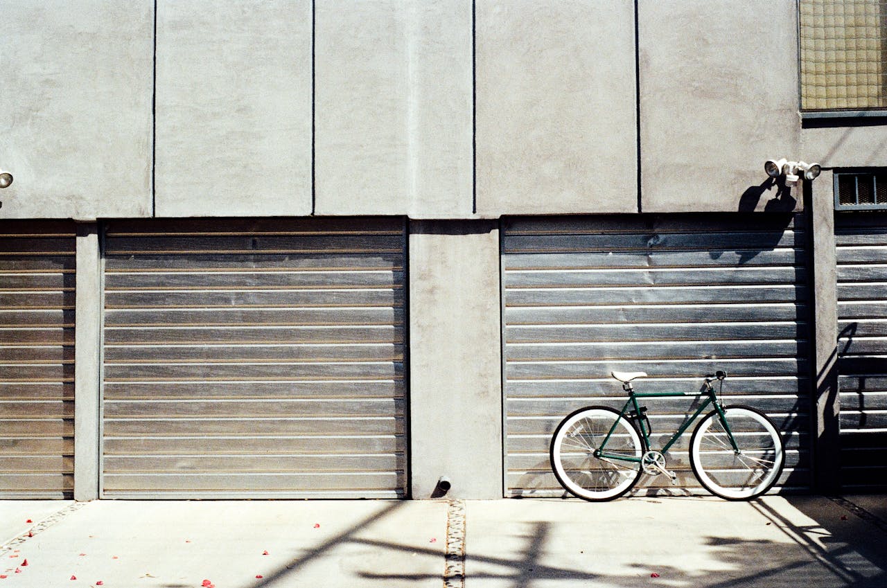 Bicycle leaning against a modern garage door, capturing urban minimalism with harsh sunlight and shadows.